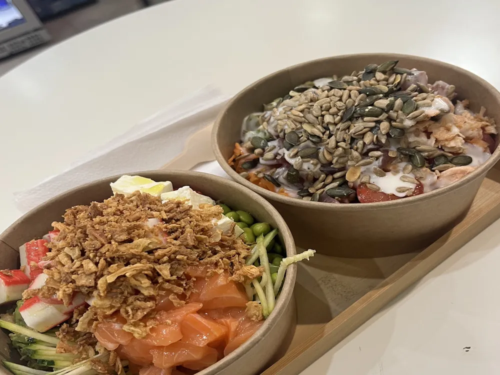 Due poke bowl sul vassoio: salmone con edamame e gamberi con semi
