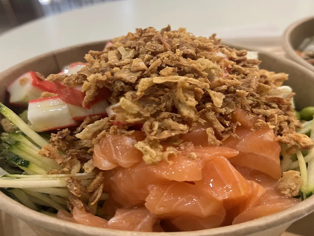 Poke bowl con salmone, cetriolo, surimi e cipolla croccante